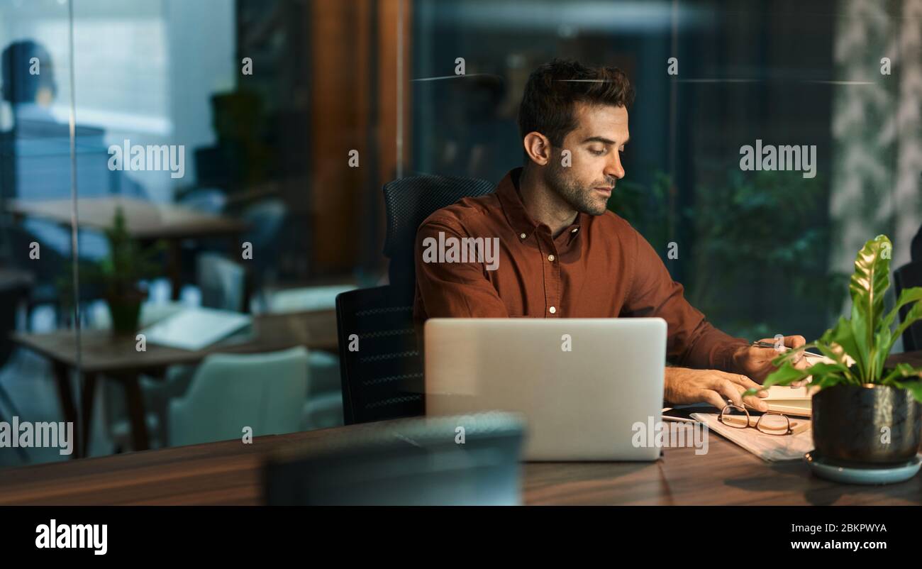 Businessman working alone in an office at night Stock Photo