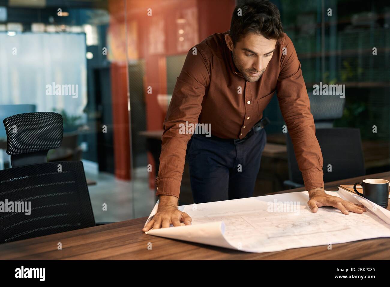 Architect leaning over an office table and reading blueprints Stock Photo