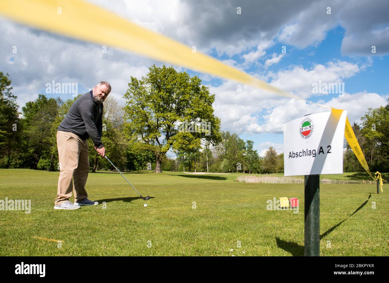 05 May 2020, Hamburg: ILLUSTRATION - Christoph Lampe, Managing Director of  the Golf Club Hamburg-Wendlohe, stands behind a barrier tape on the  Schleswig-Holstein side of the golf club at the shortened tee
