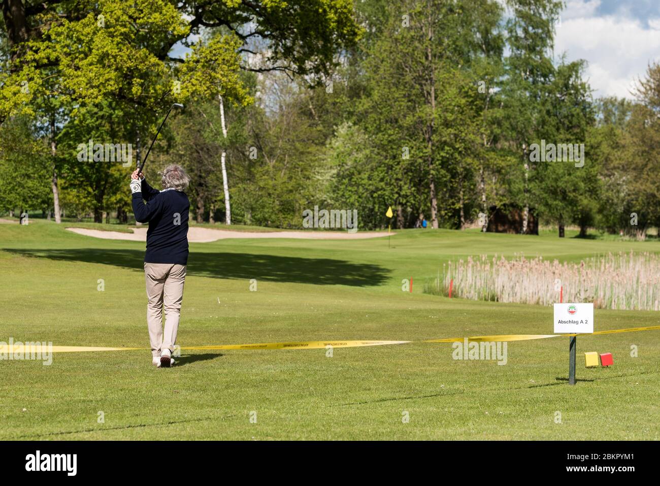 05 May 2020, Hamburg: A man hits a ball at the shortened tee A2 on the  grounds of the Hamburg-Wendlohe Golf Club behind a barrier tape on the  Schleswig-Holstein side of the
