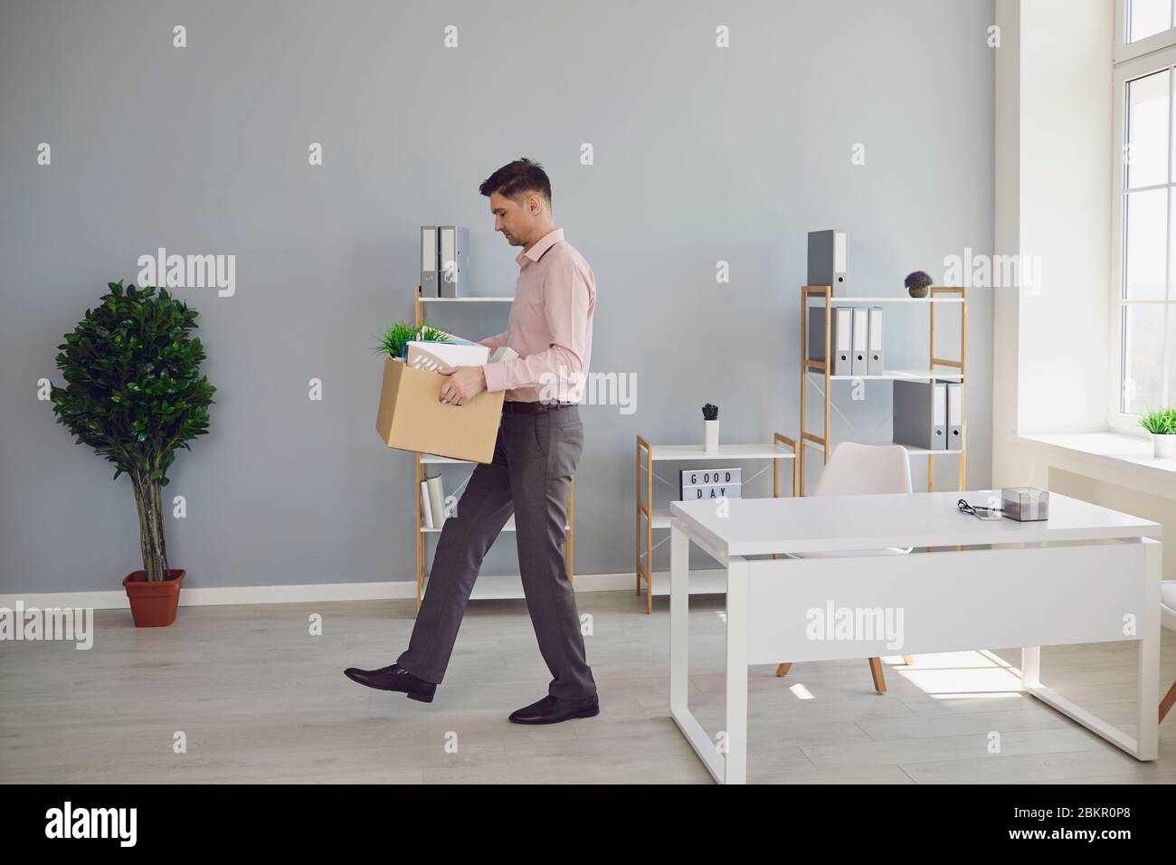 Unemployment. Dismissal. Dismissed An unemployed man with a box is walking out of the office in search of a new job. Stock Photo