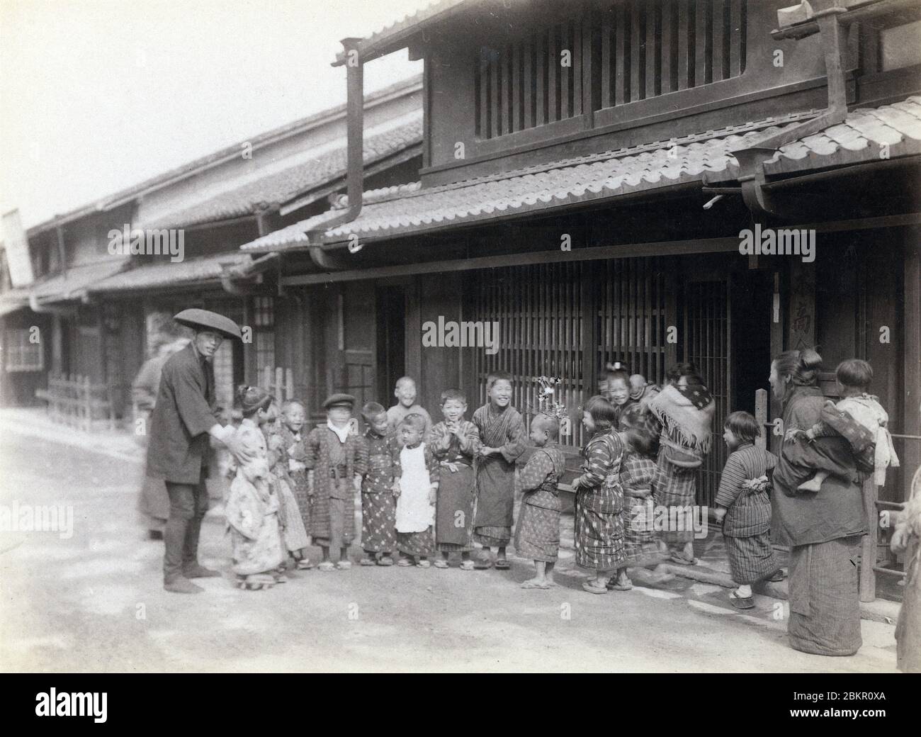 [ 1870s Japan - Japanese Children ] —   Japanese children in kimono pose before a traditional house.  19th century vintage albumen photograph. Stock Photo