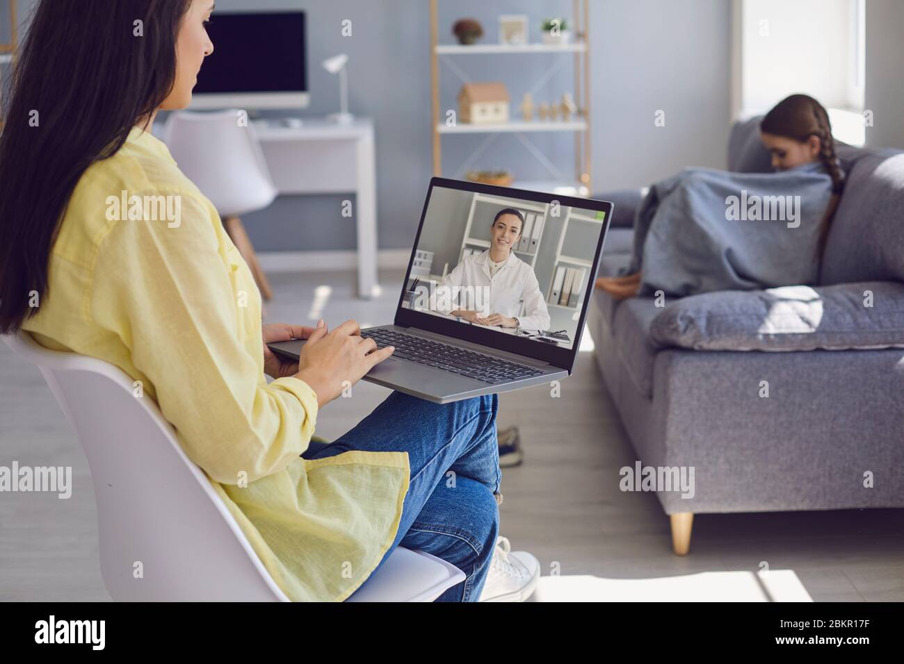 Online family doctor. Mother and girl patients consults with doctors video online chat call webcam laptop at home. Stock Photo