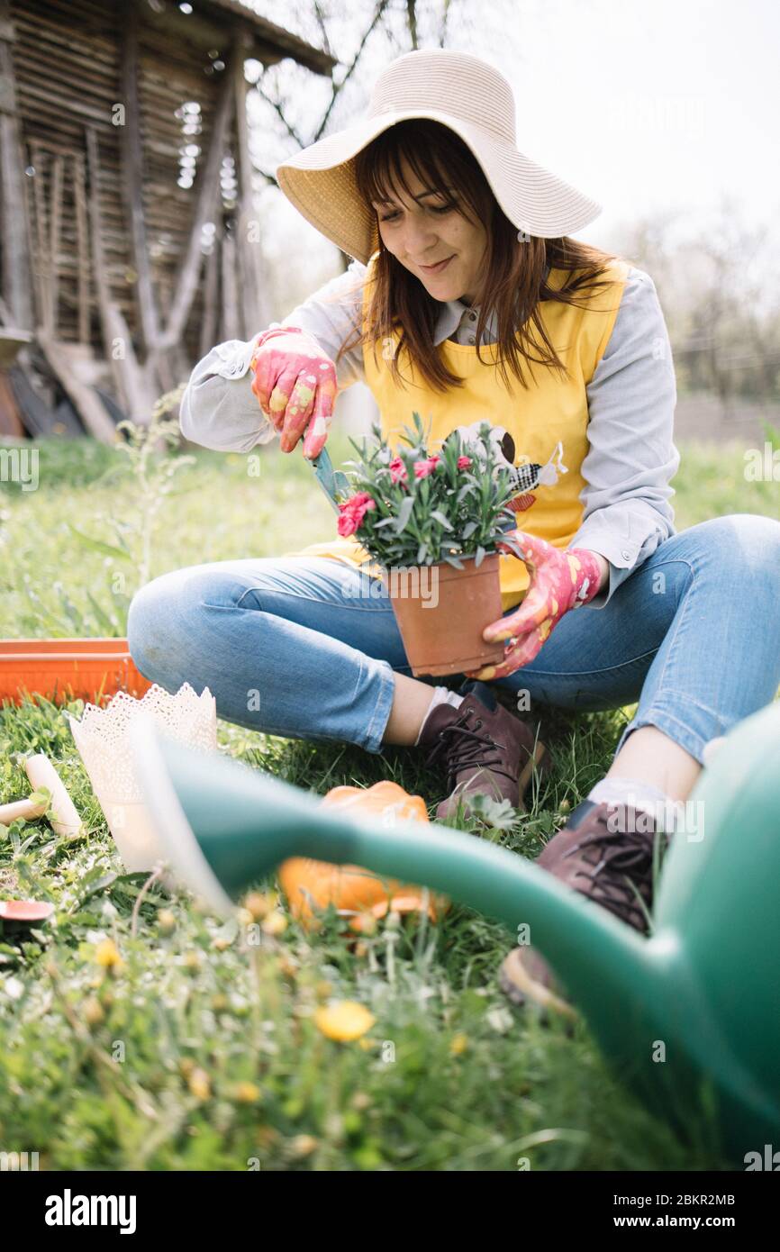 Young woman gardener planting flowers in the garden. Pretty woman ...