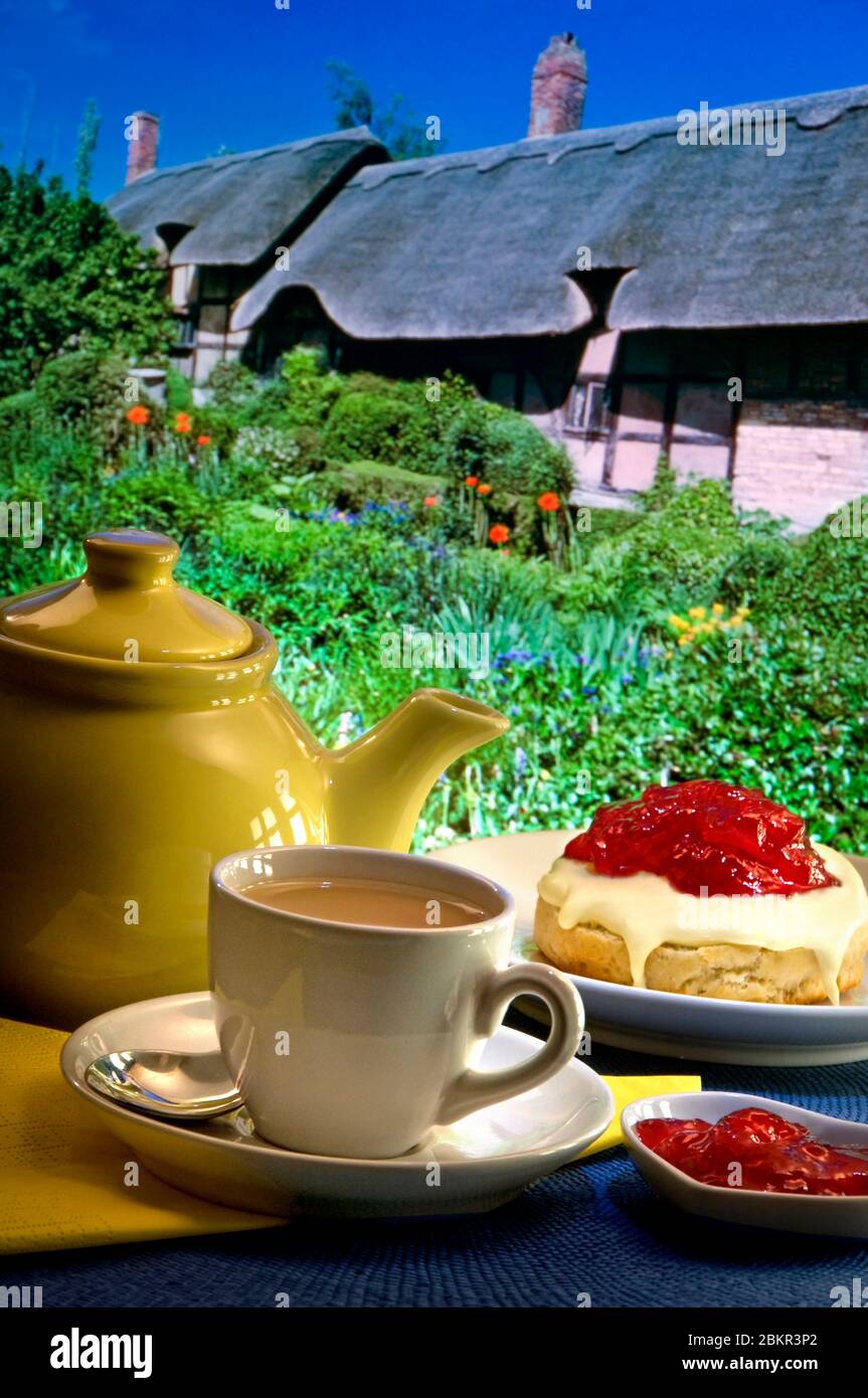 English Cream tea alfresco tea room garden Staycation outdoors terrace with traditional English thatched cottage and garden in background. England UK Stock Photo