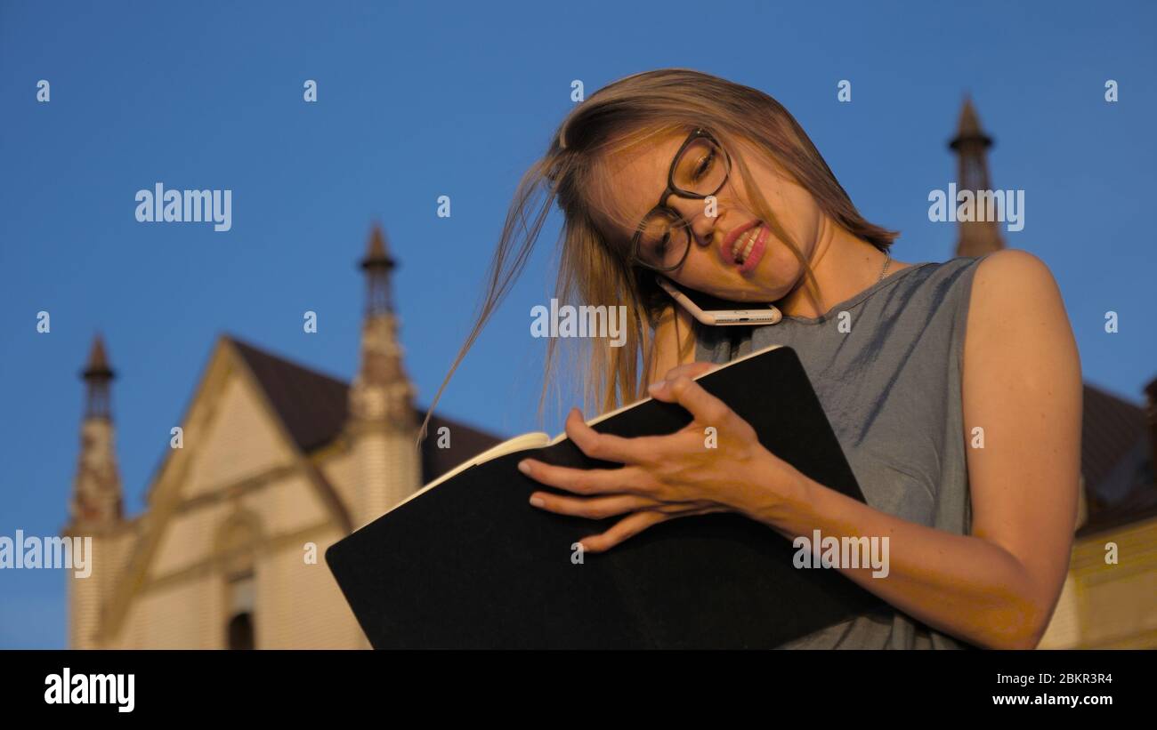 Business woman talking on the phone and makes notes outside. Stock Photo
