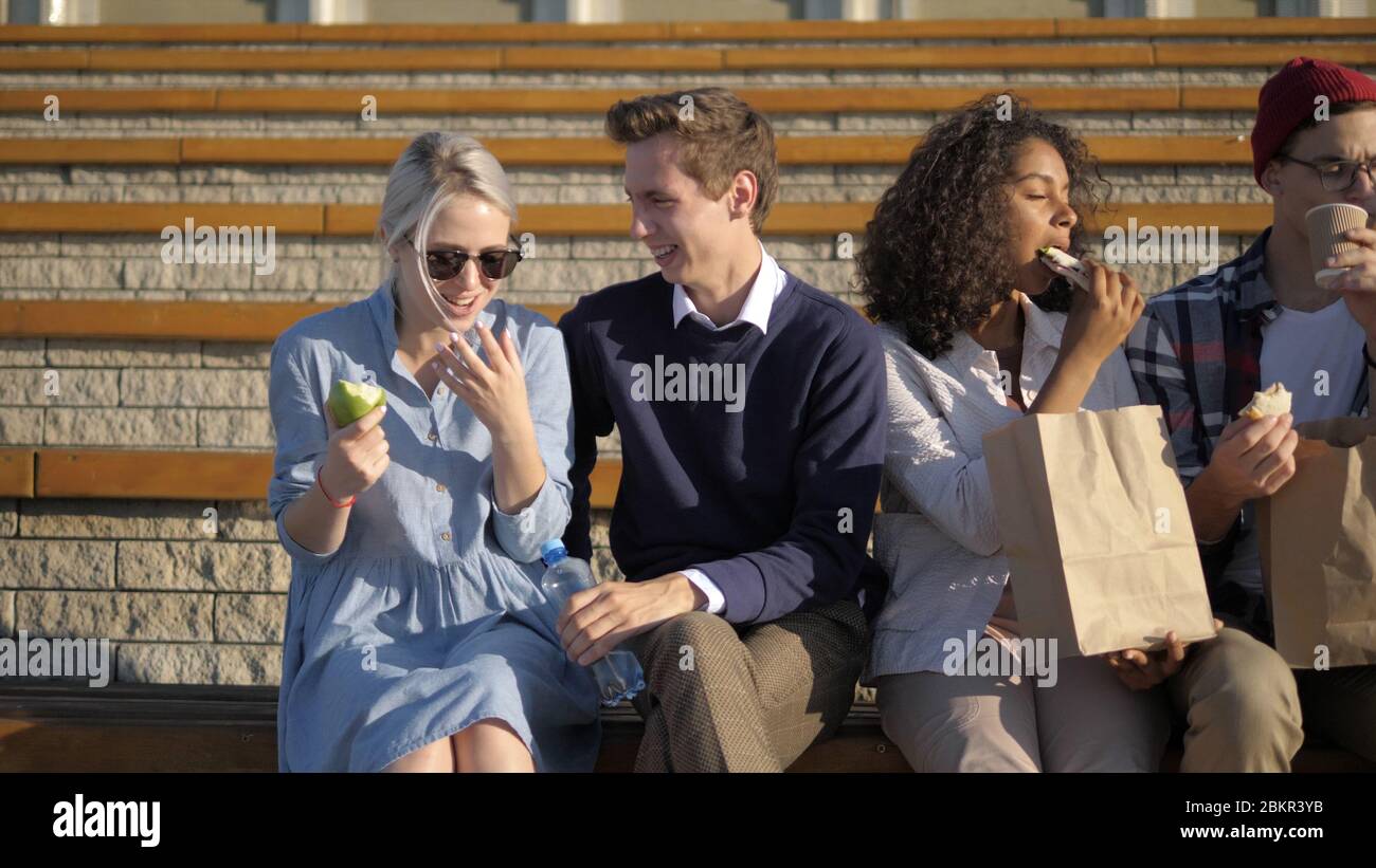 Group of students sitting in campus and eating. Stock Photo