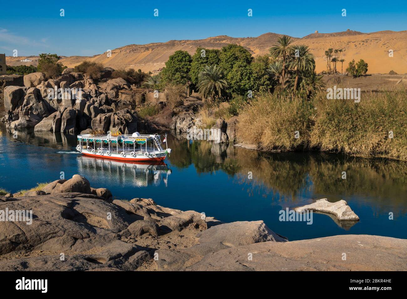 Egypt, Upper Egypt, Nile valley, Aswan, touristic boat on the Nile in front of Elephantine island with Aga Khan Mausoleum in the background Stock Photo