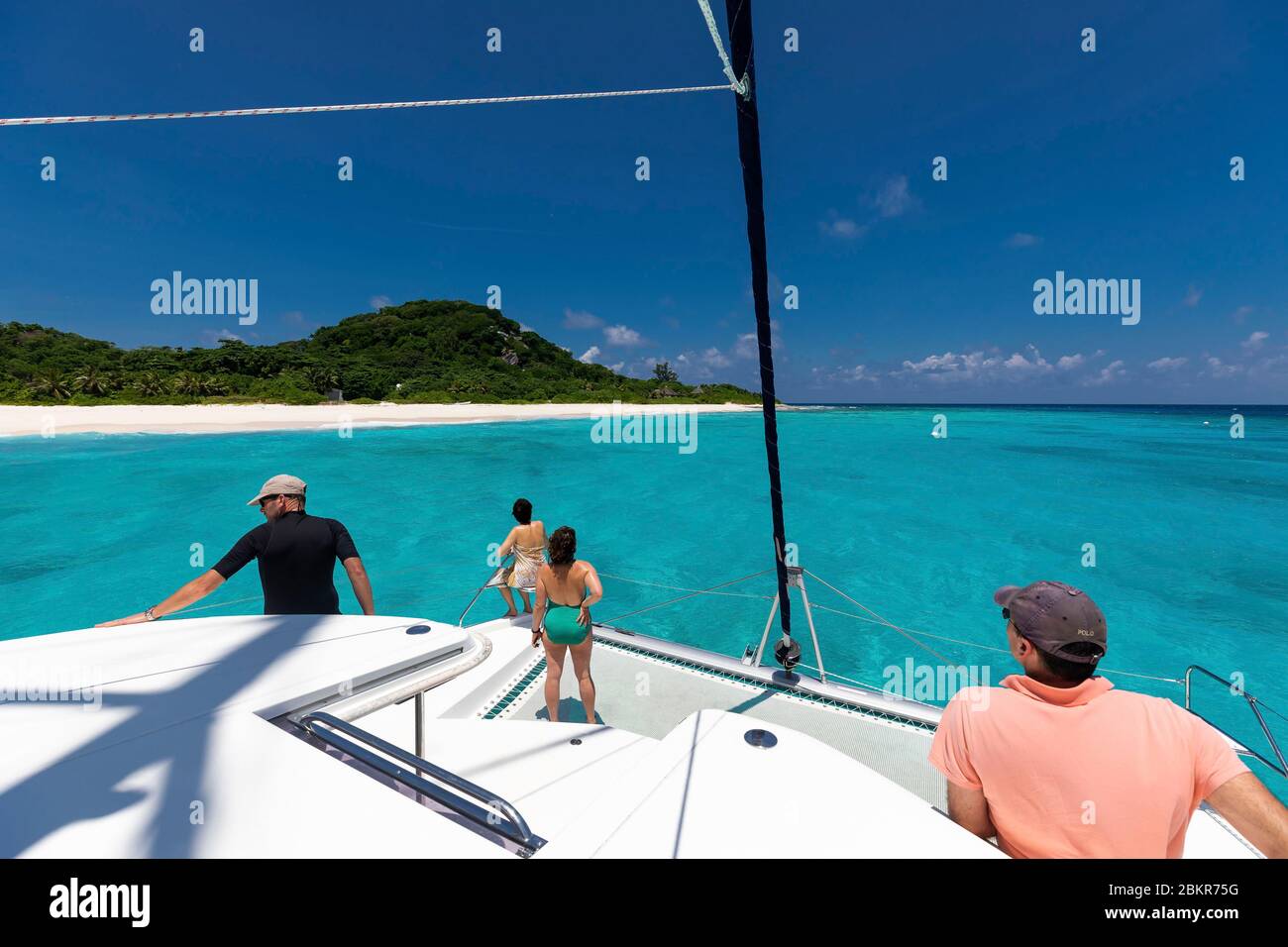 Seychelles, Cousine Island, crew aboard a boat at anchor on turquoise water Stock Photo