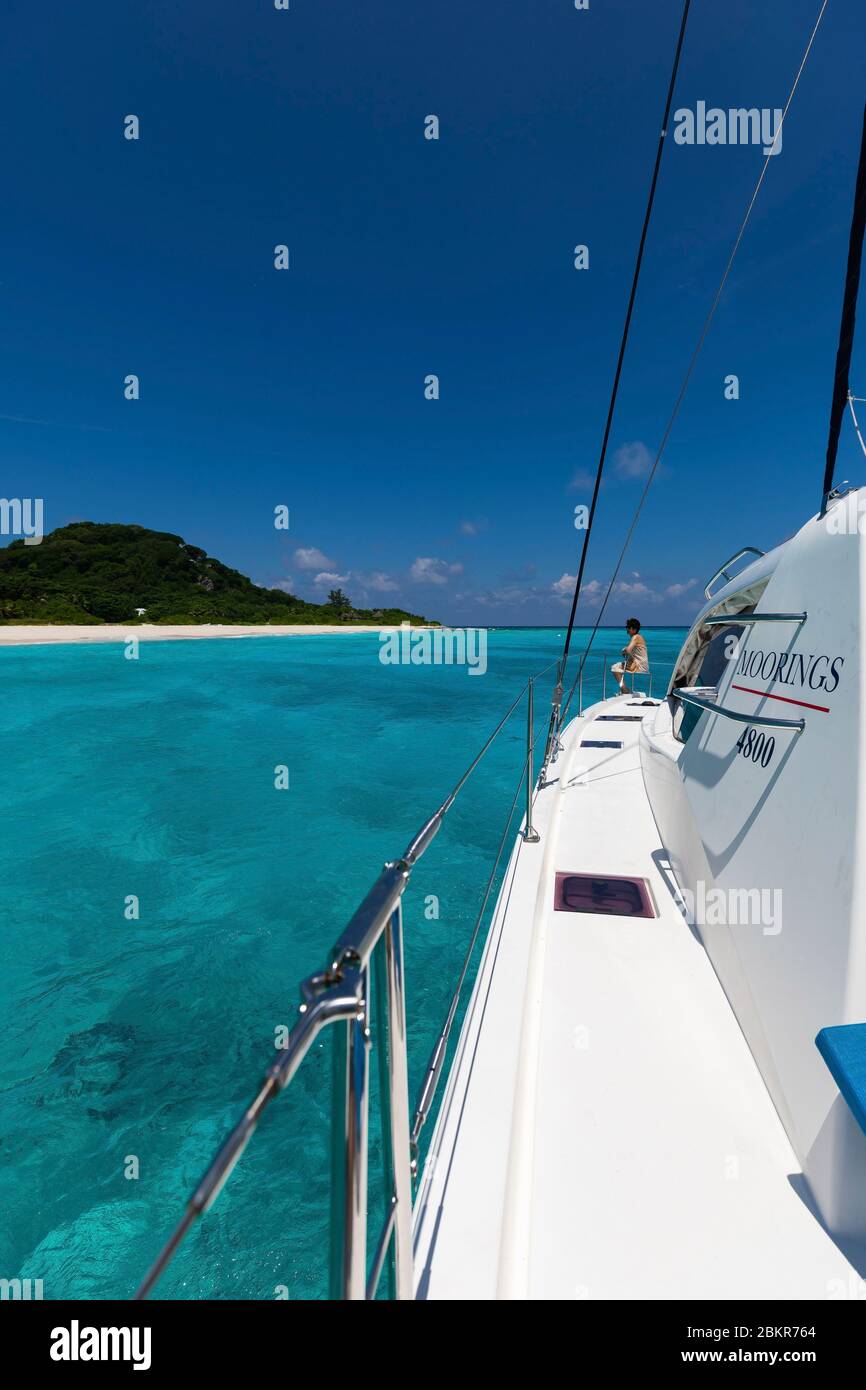 Seychelles, Cousine Island, woman aboard a boat at anchor on turquoise water Stock Photo