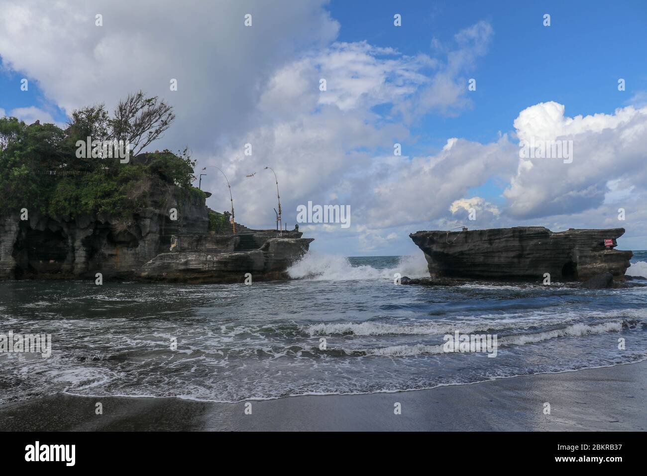 Waves shatter on a cliff at the top of which is the Hindu temple of ...