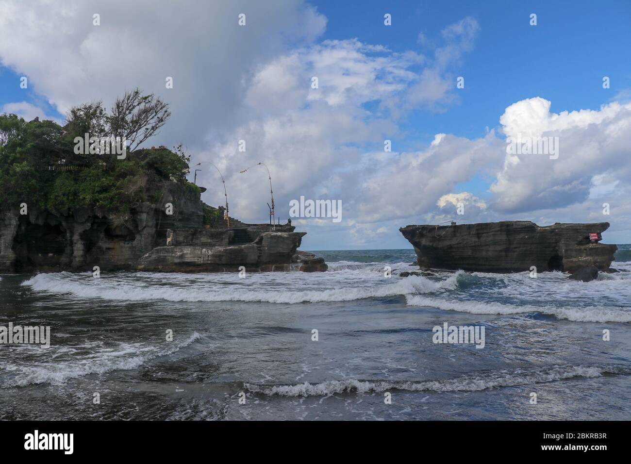 Waves shatter on a cliff at the top of which is the Hindu temple of ...
