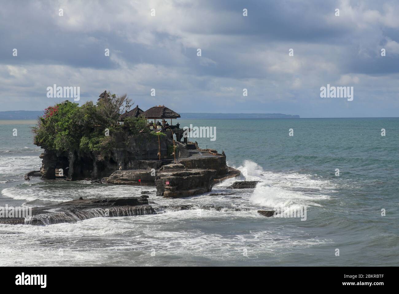 Aerial view of Tanah Lot temple on cliff in Indian ocean. Waves are ...