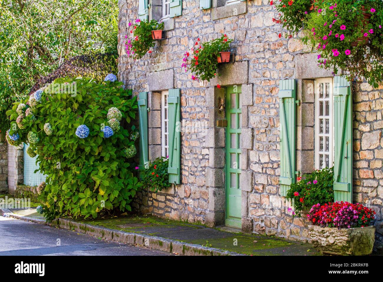 France, Morbihan, La Vraie Croix, Facade with green shutters of a flowered house with hydrangeas and geraniums Stock Photo