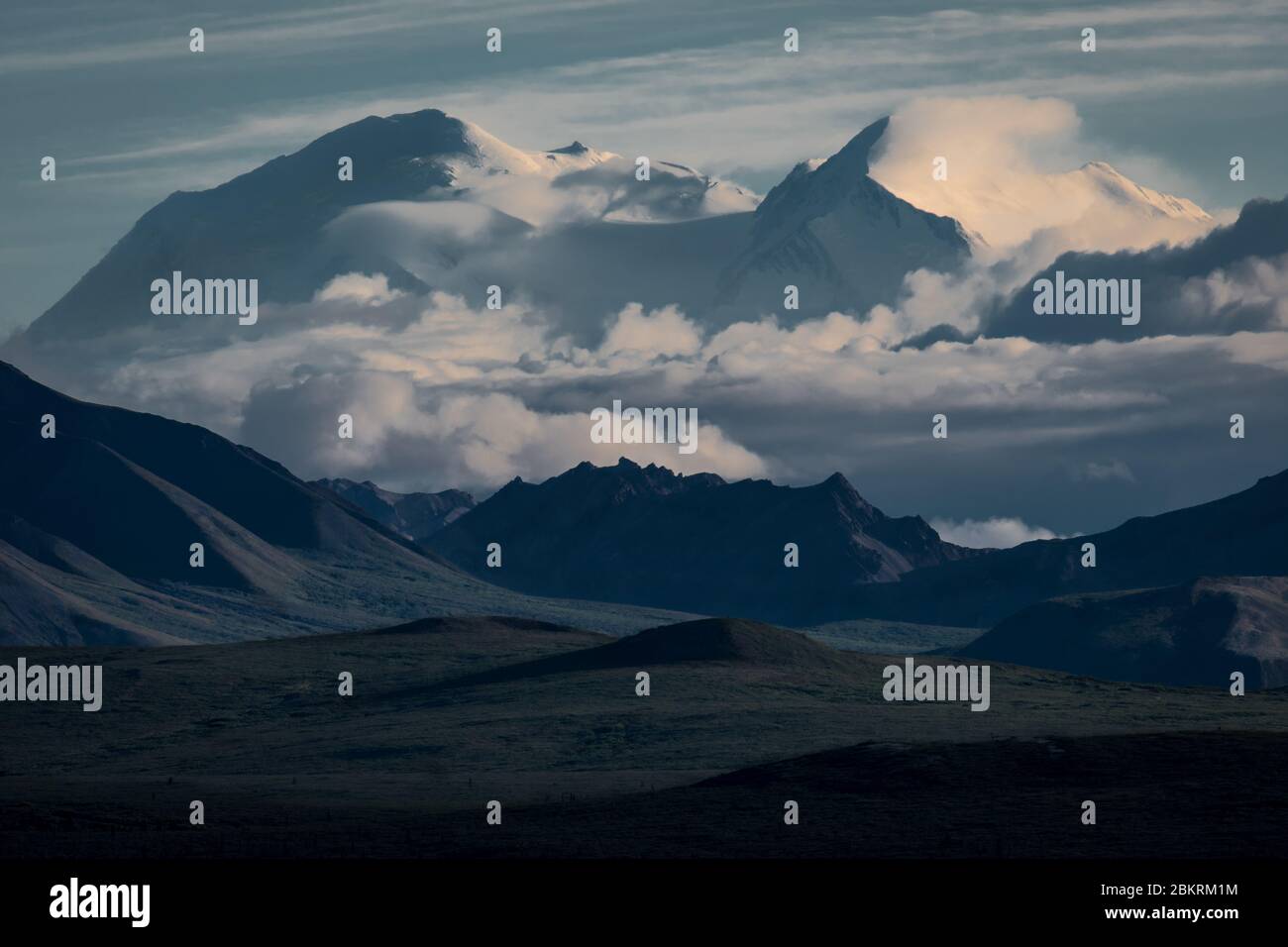 A dramatic view of Mt Denali-McKinley rising above the clouds and surrounding mountains from mile 12 in Denali Natl Park, Alaska. Stock Photo