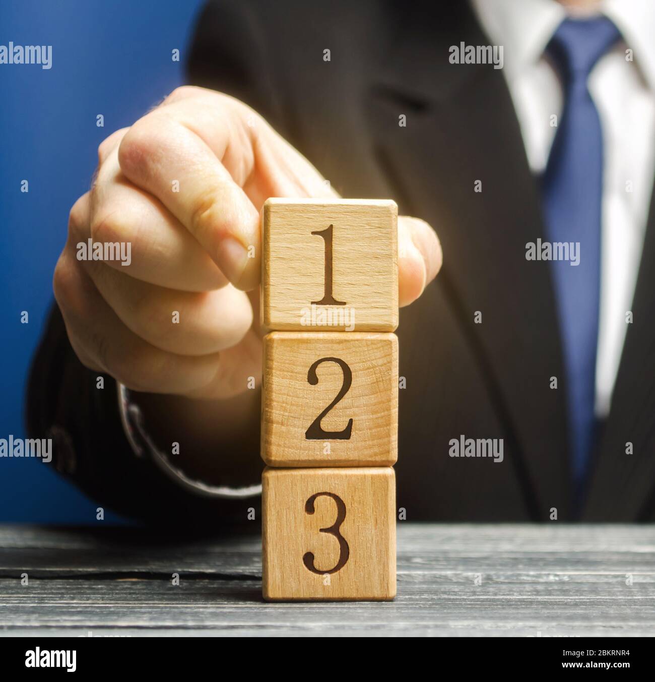Businessman puts wooden blocks with the number 1 2 3. Task list. Alternate items and conditions for implementation. Contract road map. Organization an Stock Photo