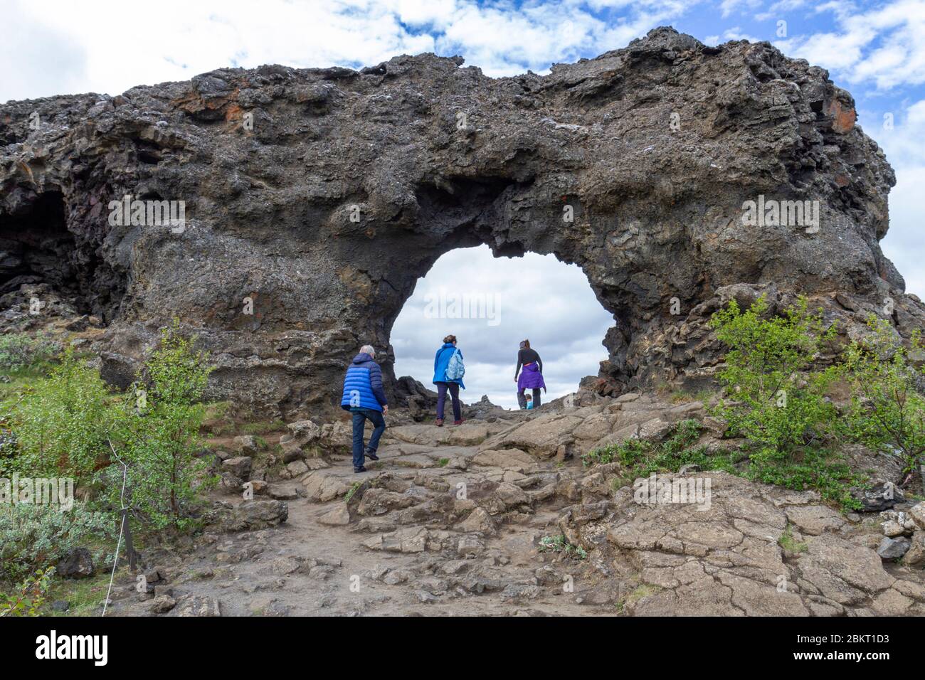 Visitors walking through the massive lava arch in the Dimmuborgir lava field, Mývatn, Iceland. Stock Photo