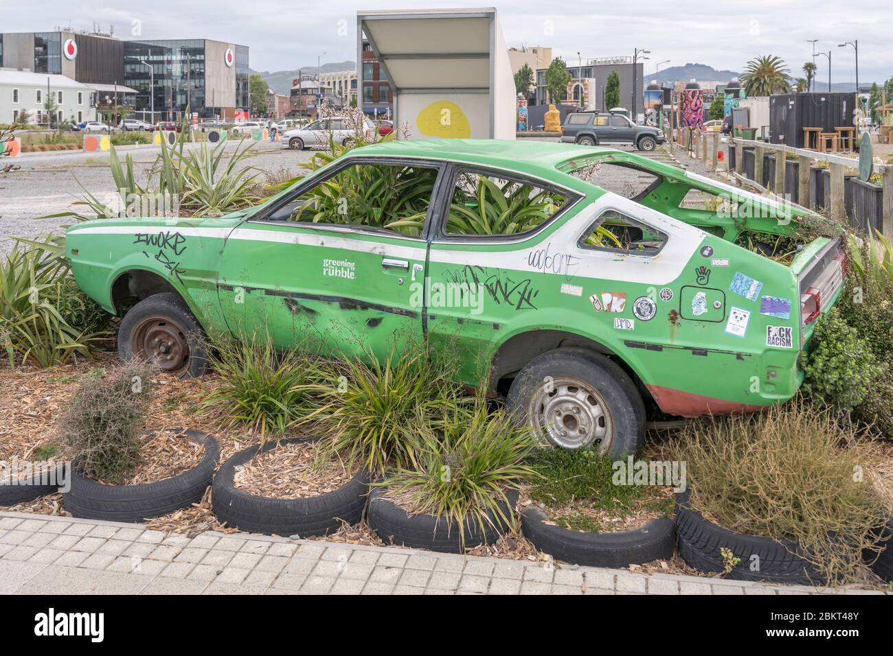 CHRISTCHURCH, NEW ZEALAND - December 02 2019: cityscape with vegetation subsuming forsaken car wreck in earthquake area, shot in bright cloudy light o Stock Photo