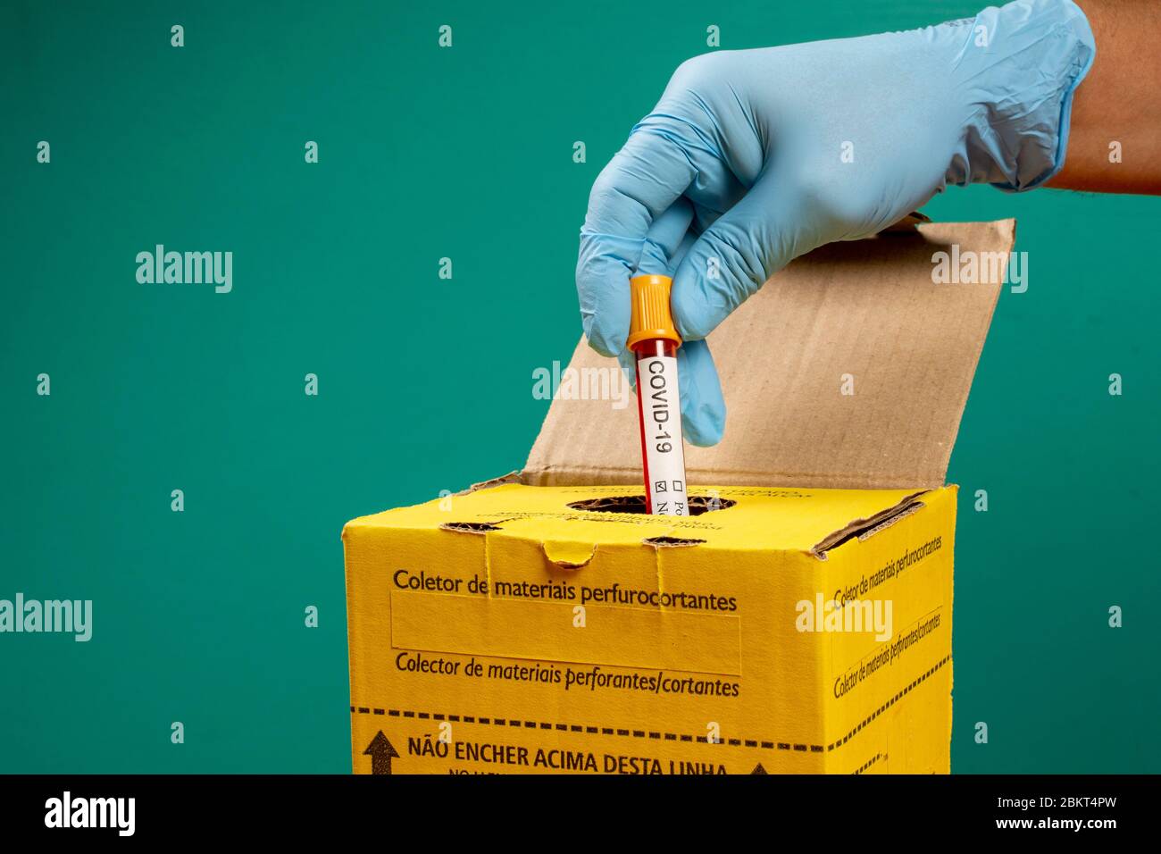 doctor throwing out vacuum tube in an infectious waste disposal box