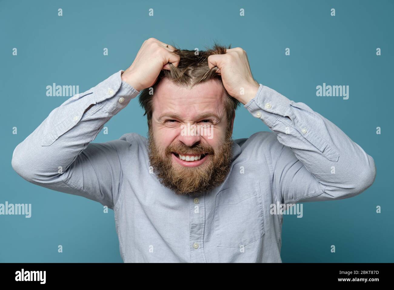 Man is angry and experiencing stress, he furiously rips out his hair ...