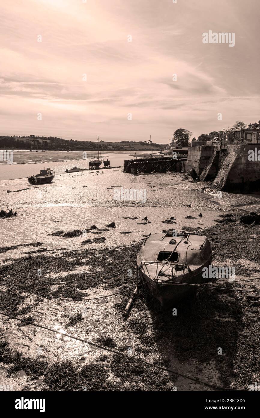 A view of a beached sailing vessel at Appledore, Devon when the tide is out marooned on the mud which is depicted in sepia tones Stock Photo