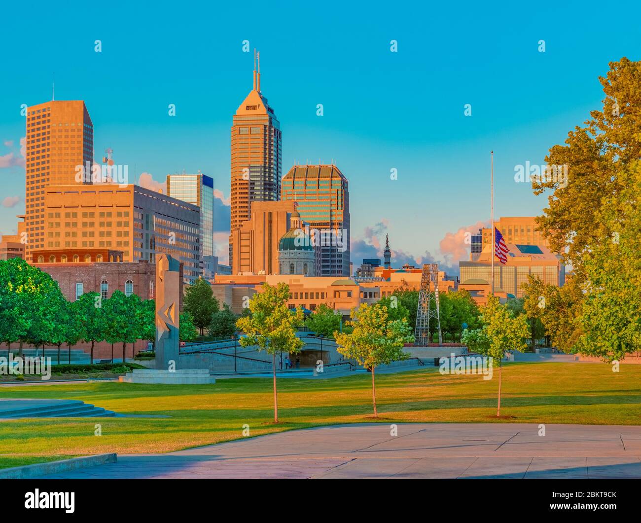 Dusk light hits the buildings in the skyline of Indianapolis, Indiana, from the White River State Park. The grass, trees and capitol building glow. Stock Photo