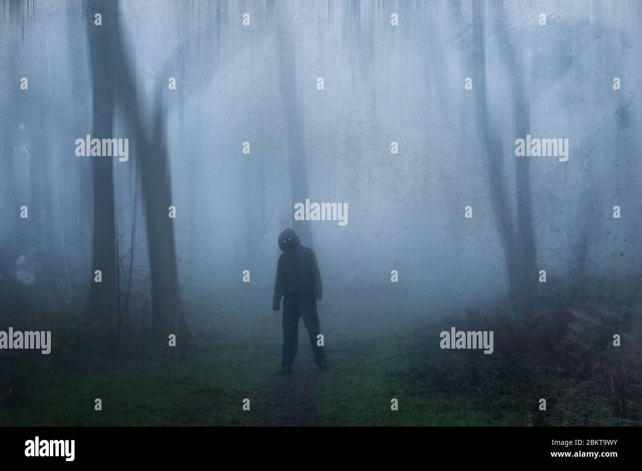 A mysterious spooky hooded figure with glowing eyes standing in a ...