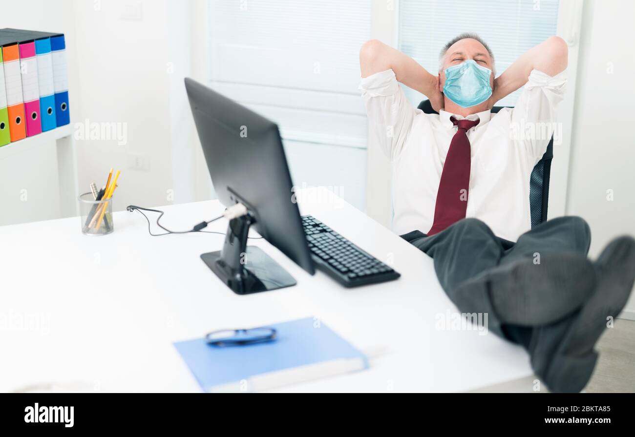Businessman relaxing in his office during coronavirus pandemic Stock Photo