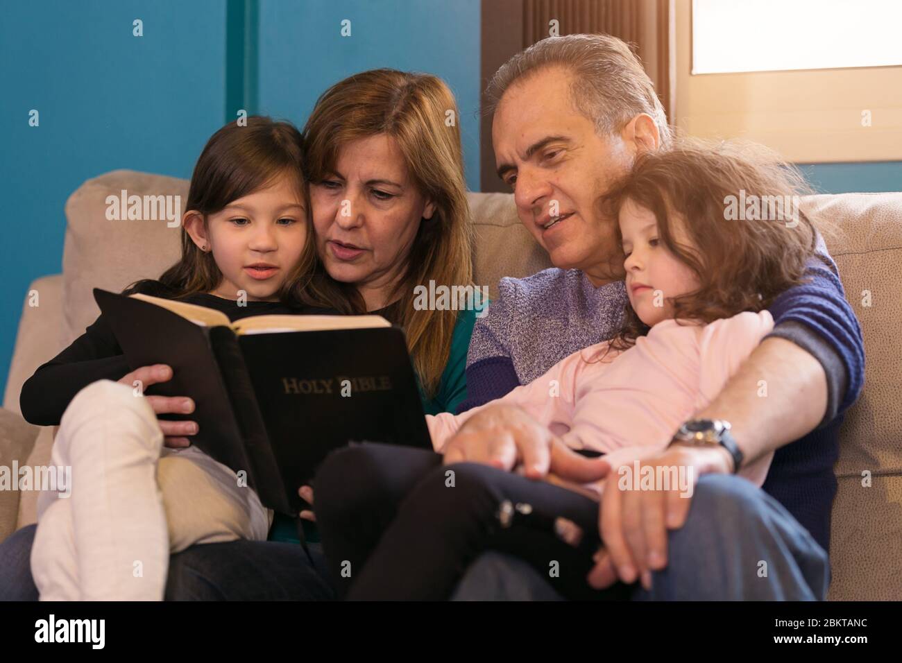 Grandparents teaching grandchildren about the Holy Bible Stock Photo