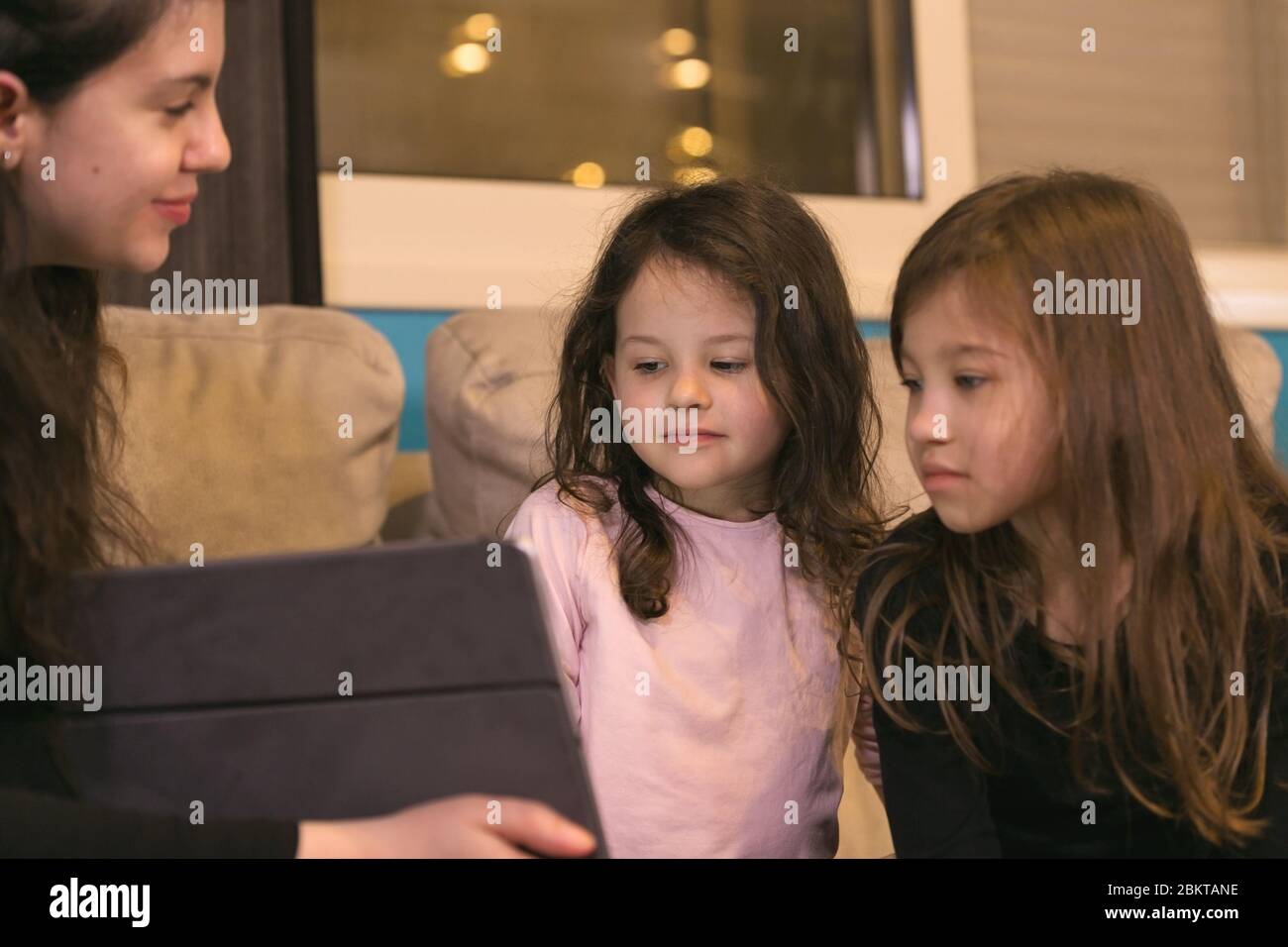 Young Mother teaching children at home on Electronic Device Stock Photo
