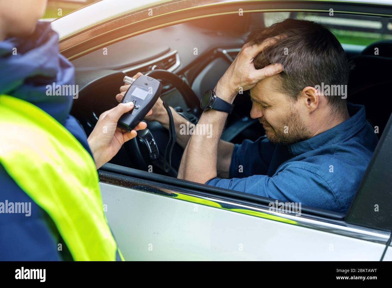 drink and drive concept - sad drunk man sitting in the car after police alcohol test with alcometer Stock Photo