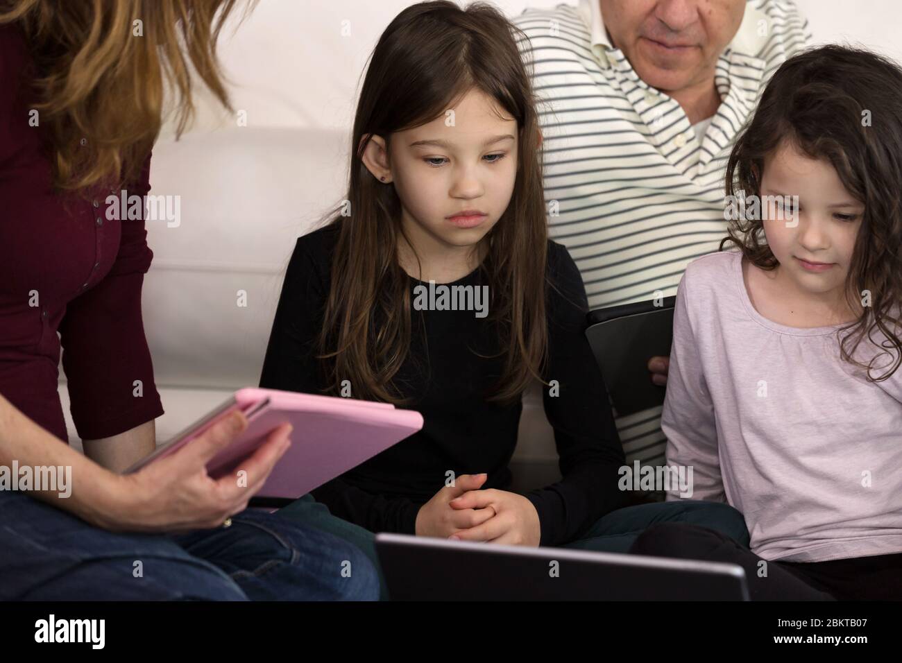 Family teaching children at home on Electronic Devices Stock Photo