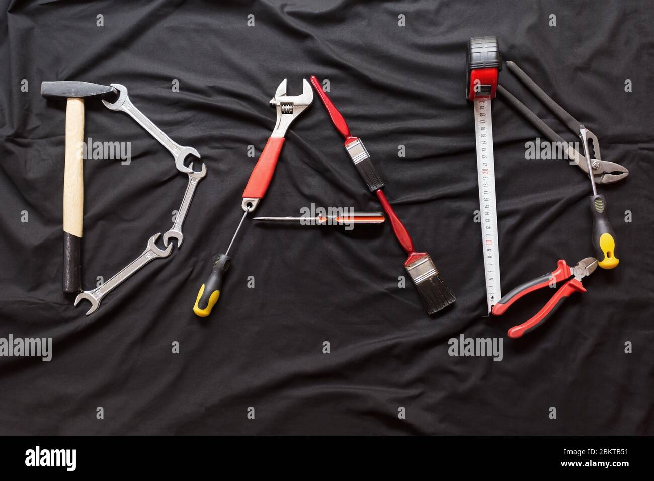 The word dad spelled out with different hand tools on Black background Stock Photo