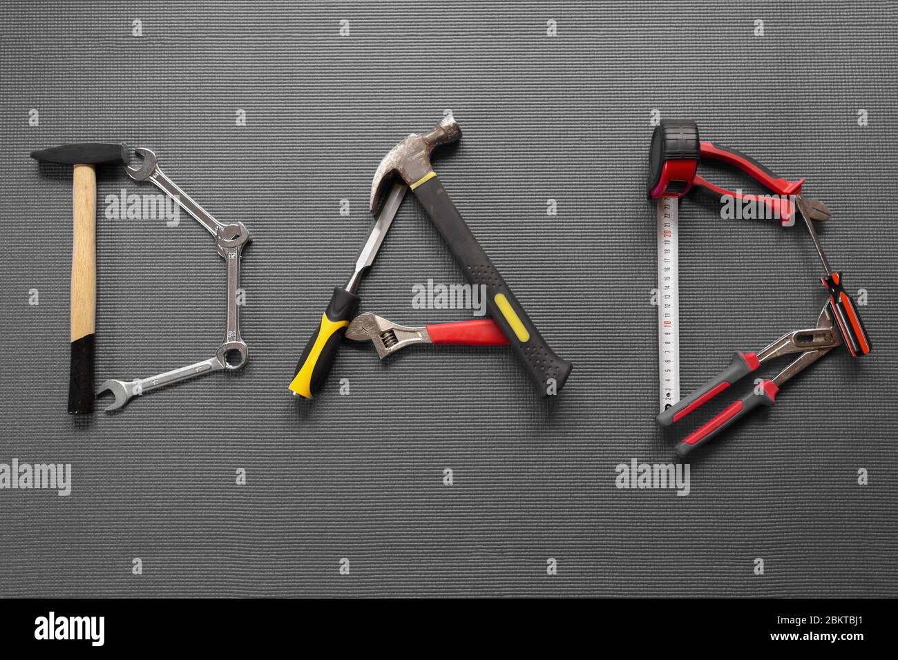 The word dad spelled out with different hand tools on Grey background Stock Photo