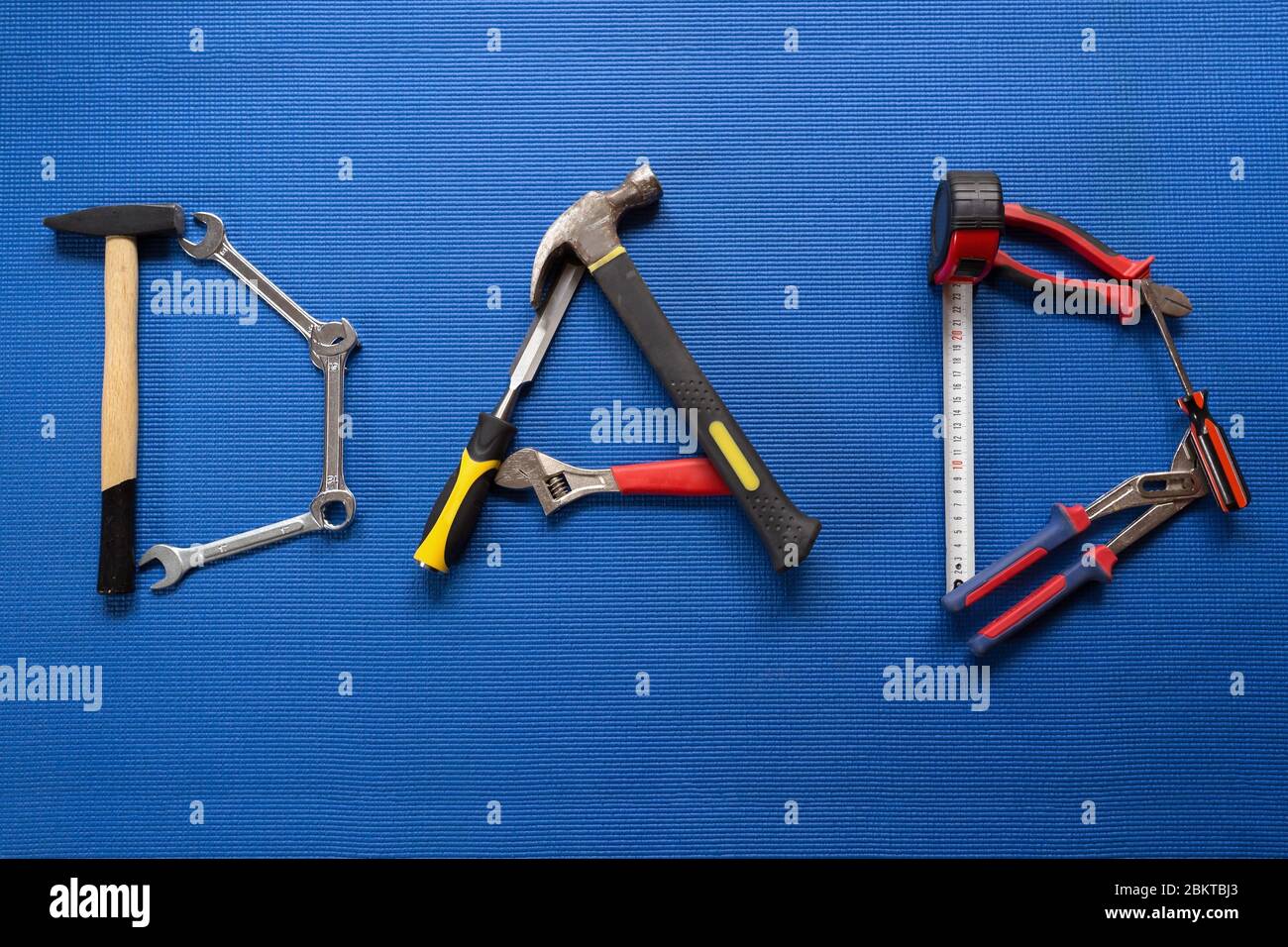 The word dad spelled out with different hand tools on Blue background Stock Photo