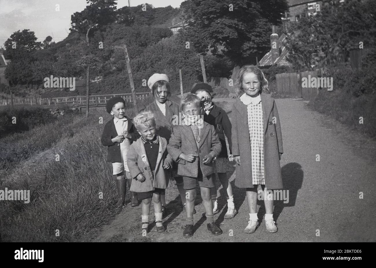 1940s, historical, Standing ouutdoors on a footpath, a small group of young children, with the little boy in a pair of shorts and jacket at the front looking like he is their leader.  Growing up in Britain this era, children had the freedom to play with their friends outdoors, having a kind of 'childhood gang' that later generations would miss. They could have adventures with their mates, growing up heathly, active, involving imagination and play. Stock Photo