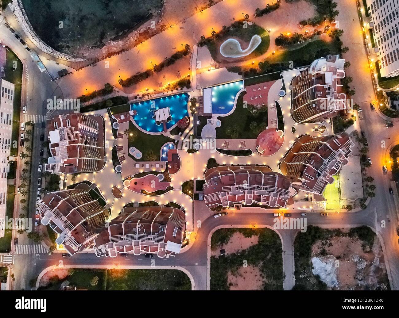 Drone point of view aerial photography modern luxury architectural residential complex with swimming pools near Mediterranean Sea beach nightview Stock Photo