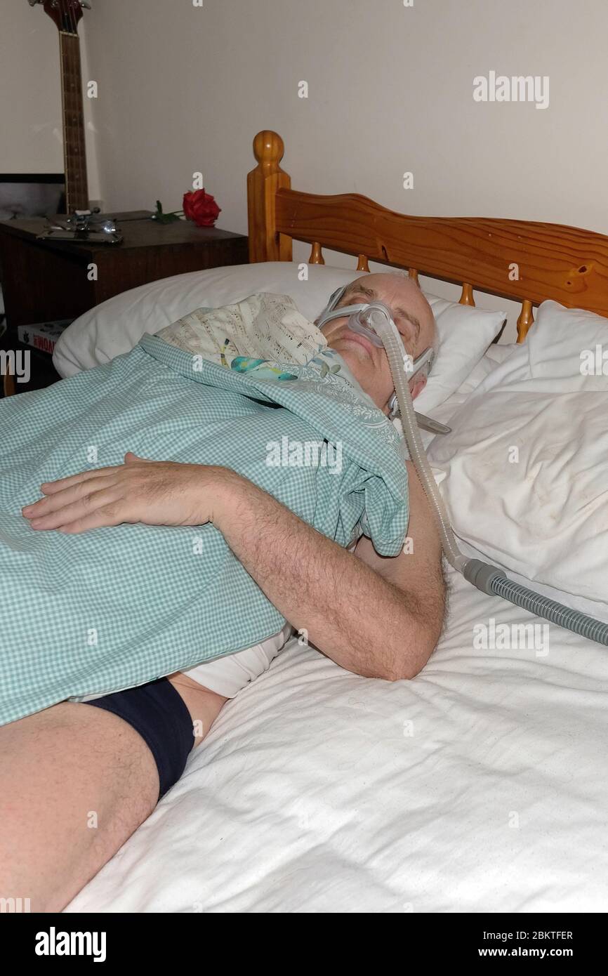 May 2020 - Mature man fast asleep wearing the mask of a CPAP sleep apnea machine @ 02.45am Stock Photo