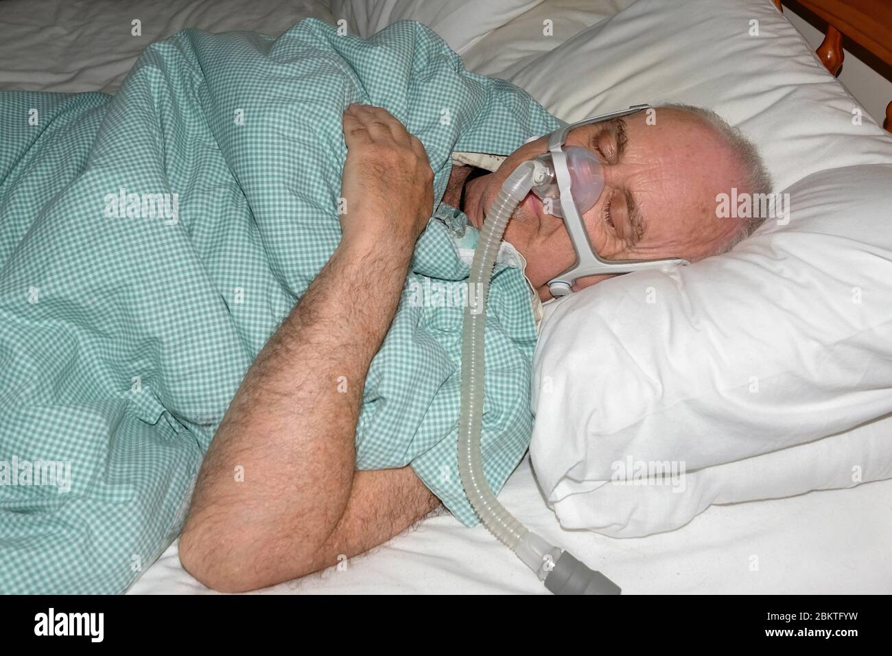 May 2020 - Mature man fast asleep wearing the mask of a CPAP sleep apnea machine @4.15am Stock Photo