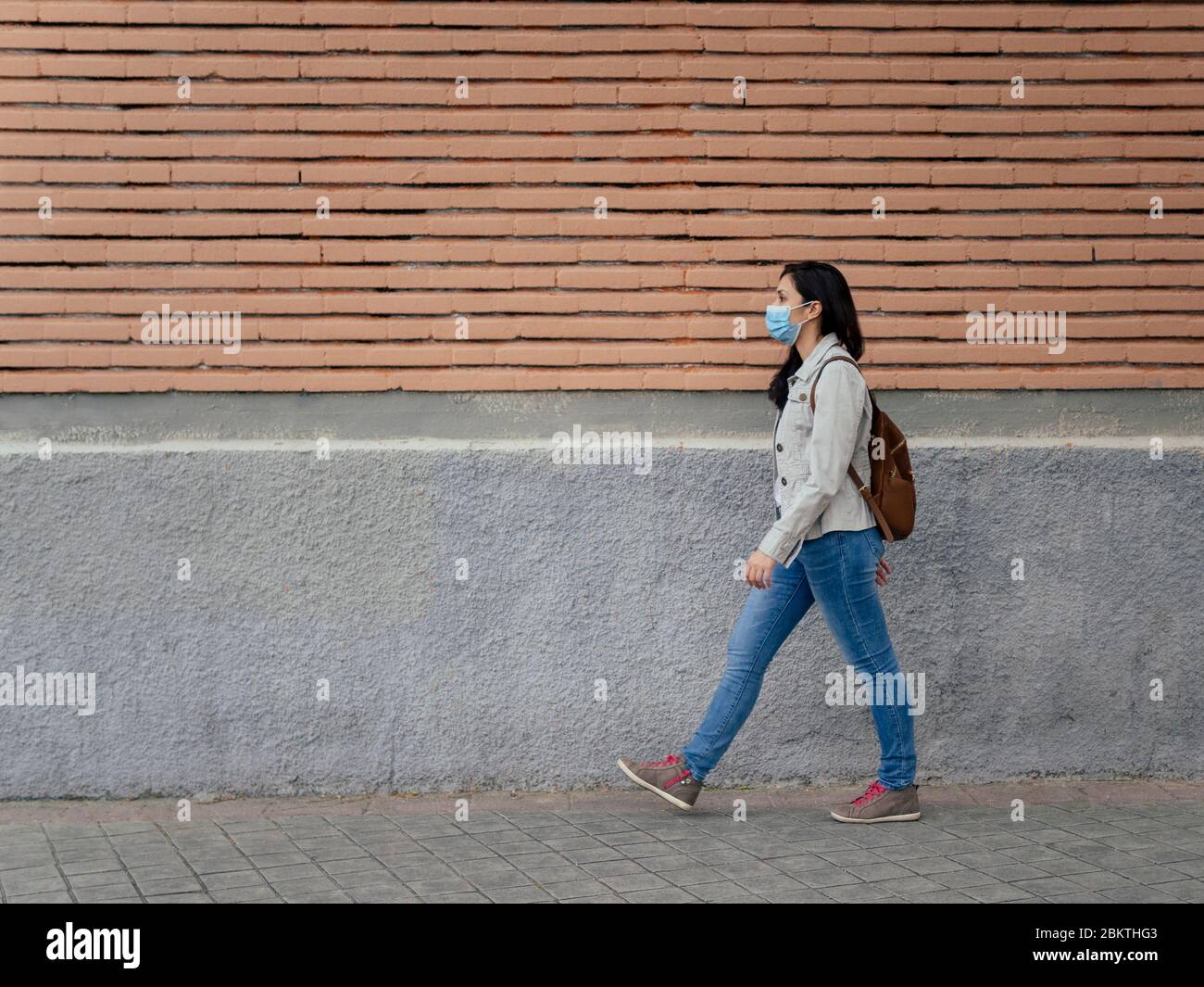 Woman walking in the street. She is wearing a protective mask for the prevention of a virus. Coronavirus concept. Stock Photo