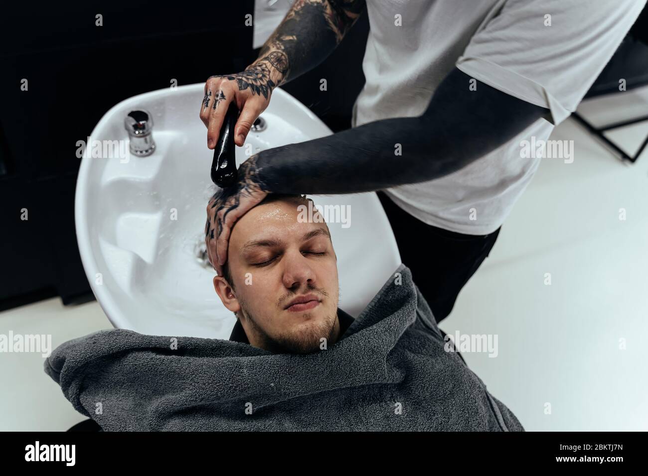 Attractive male is getting a modern haircut in barber shop. Top view of a young man getting his hair washed and his head massaged in a hair salon Stock Photo