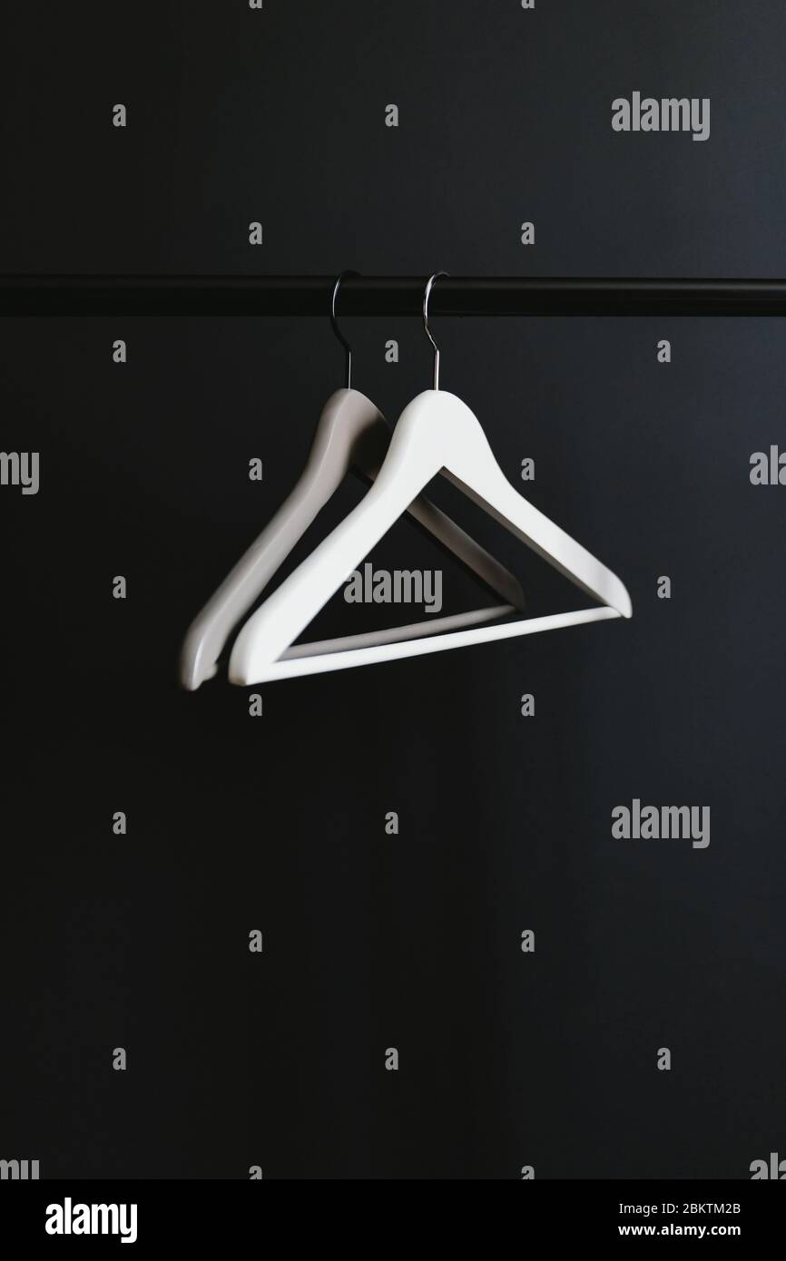 White And Grey Hangers Without Clothes On A Crossbar Against Black Wall Stock Photo Alamy