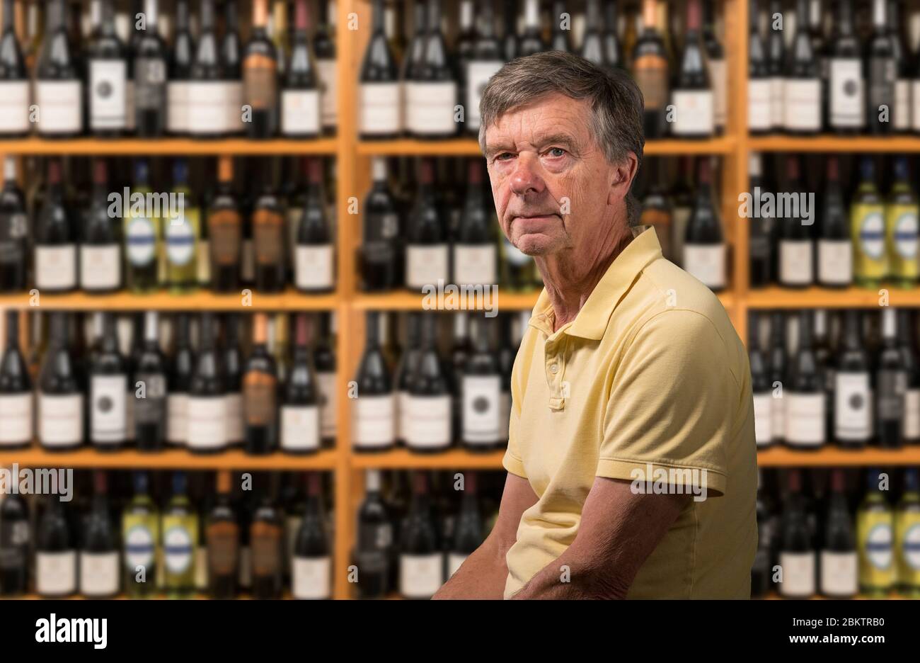 Senior old man looking at camera with a background of a wine cellar