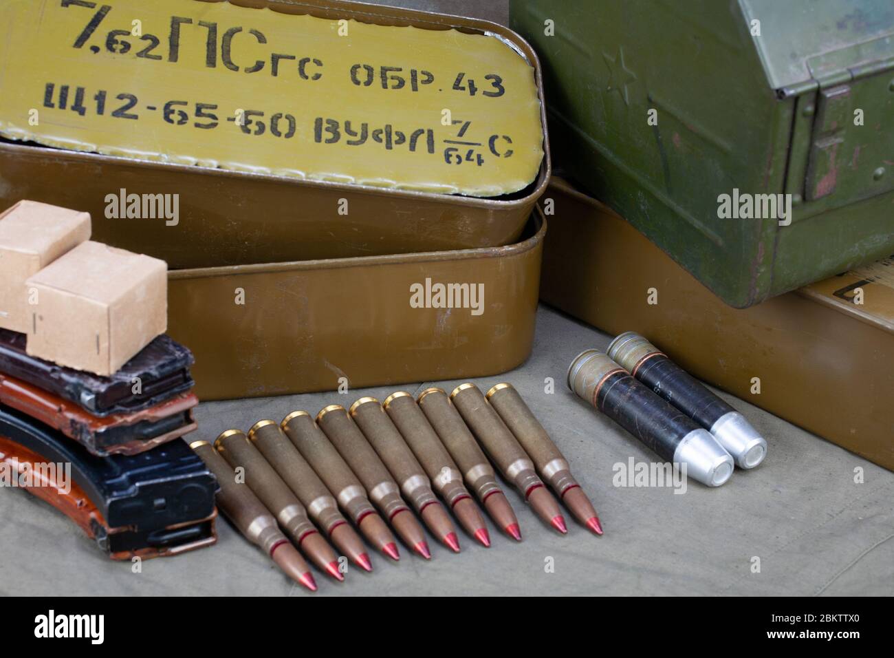 12.7×108mm cartridges for a 12.7 mm heavy machine gun DShK used by the former Soviet Union with another ammunition on green background. Text in russia Stock Photo