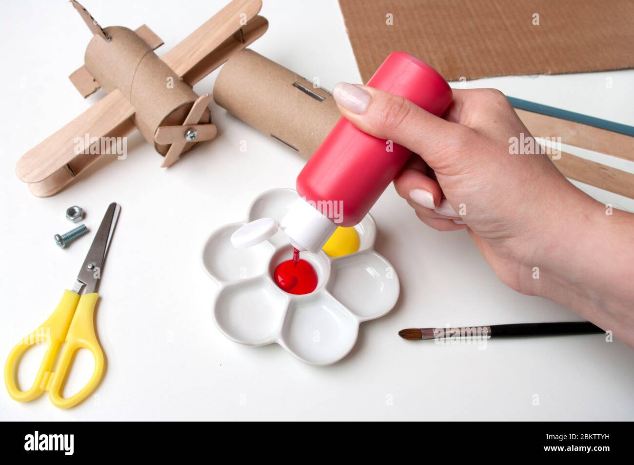 How to make airplane. Hand made toy,zero waste from toilet paper roll and popsicle sticks. For kids and parents. Step 5,put red paint. Stock Photo