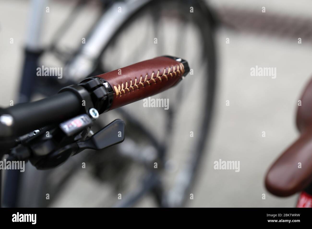 Closeup color image of bicycle handlebar with brown leather details and black ring bell, Baden, Switzerland, March 2020. Bicycles are great exercise. Stock Photo