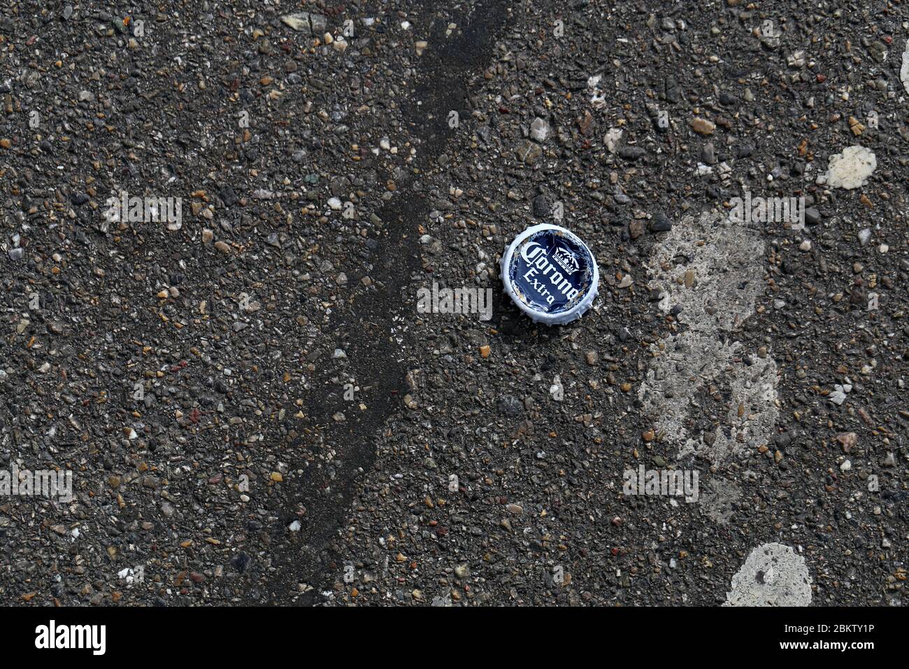 Corona beer bottle cap on an asphalt road, Zürich, Switzerland, March 2020. Photographed from above. Stock Photo