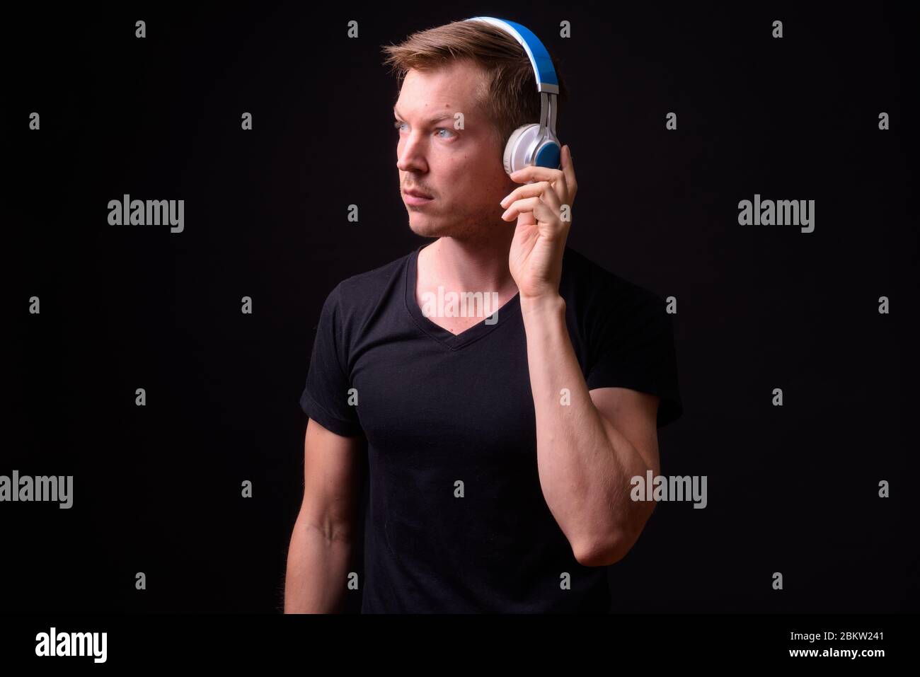 Portrait of young handsome man thinking and listening to music Stock Photo