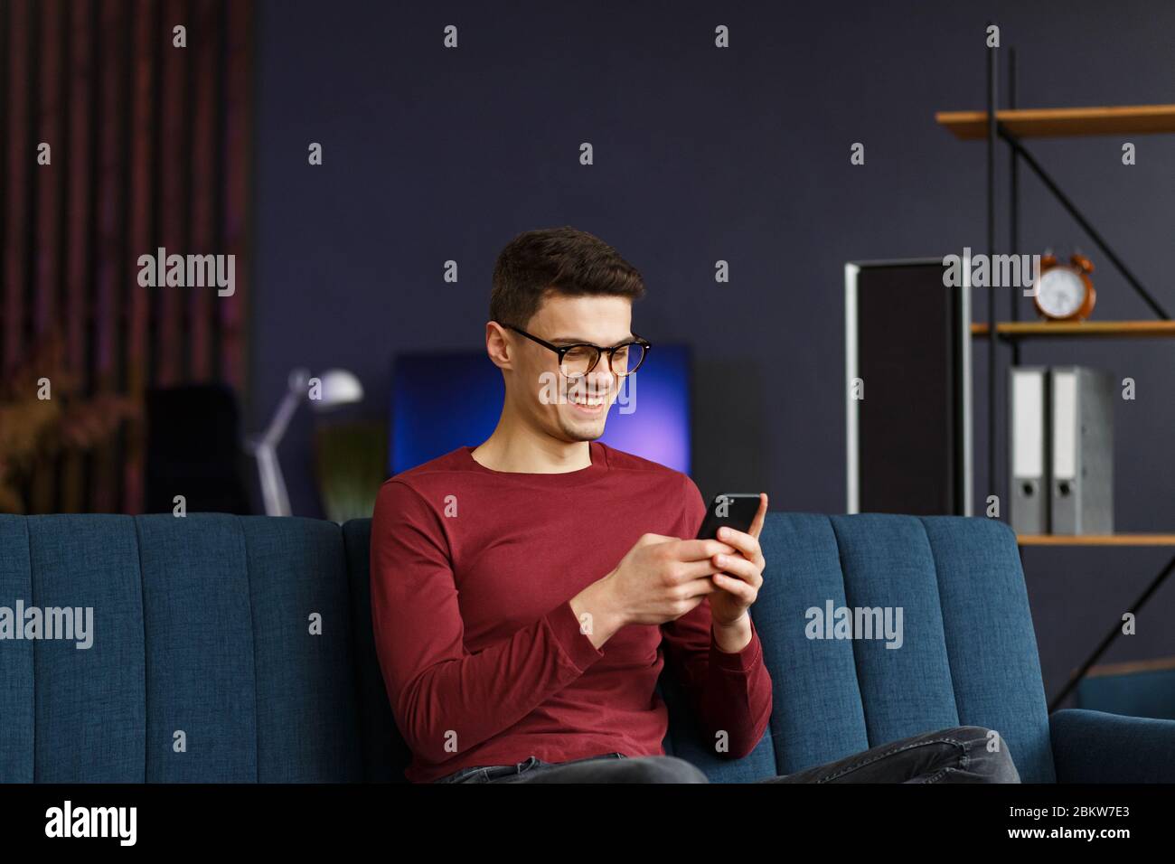 Young freelancer using smartphone and smiling. Happy man using m Stock Photo