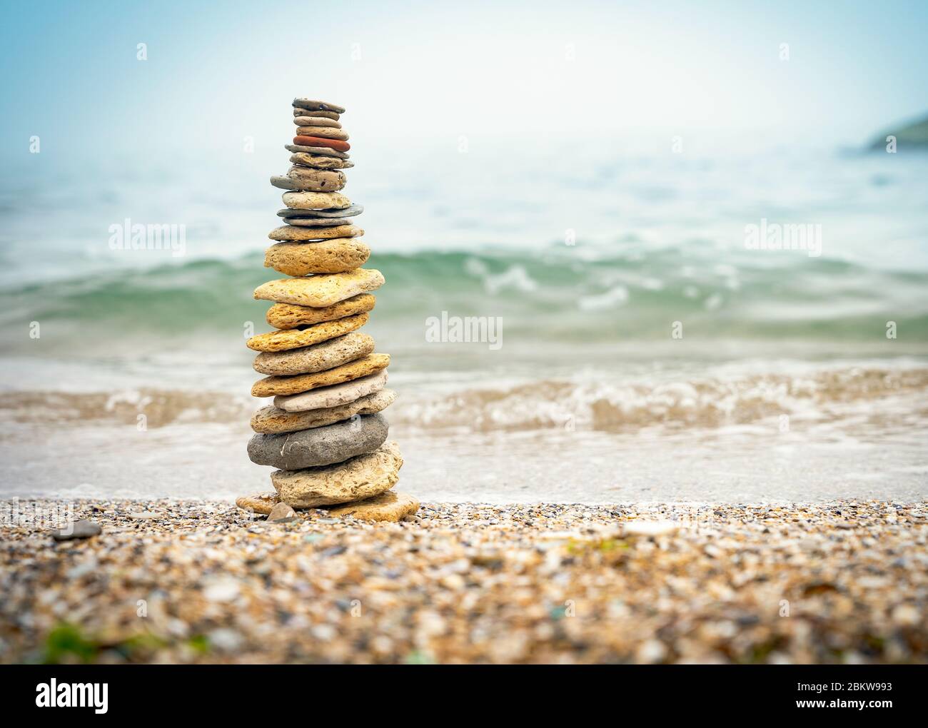 Stones pyramid on sand symbolizing zen, harmony, balance. Positive energy. Ocean in the background Stock Photo